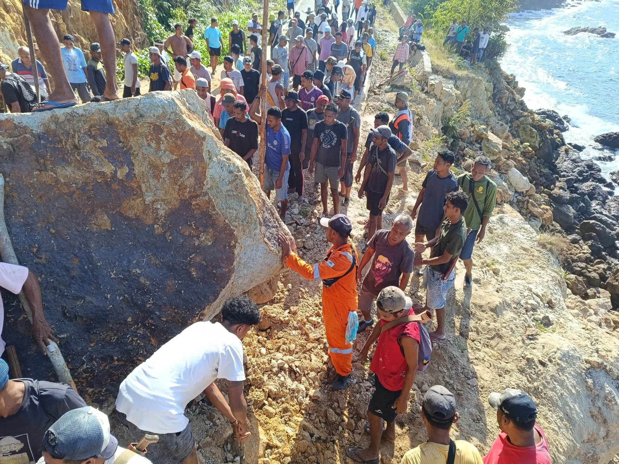 Warga mengamati batu besar yang menutup bagian jalan